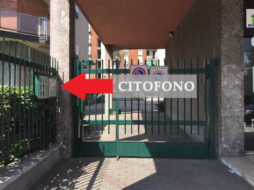 Cancello del cortile condominiale con il pannello citofoni indicato dalla freccia