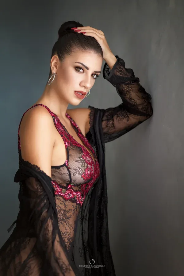 Ritratto erotico in stile rock in bianco e nero, modella in rete accovacciata su uno sgabello